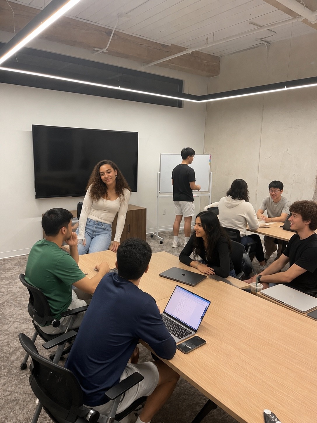 A collaborative working session with participants seated around tables using laptops